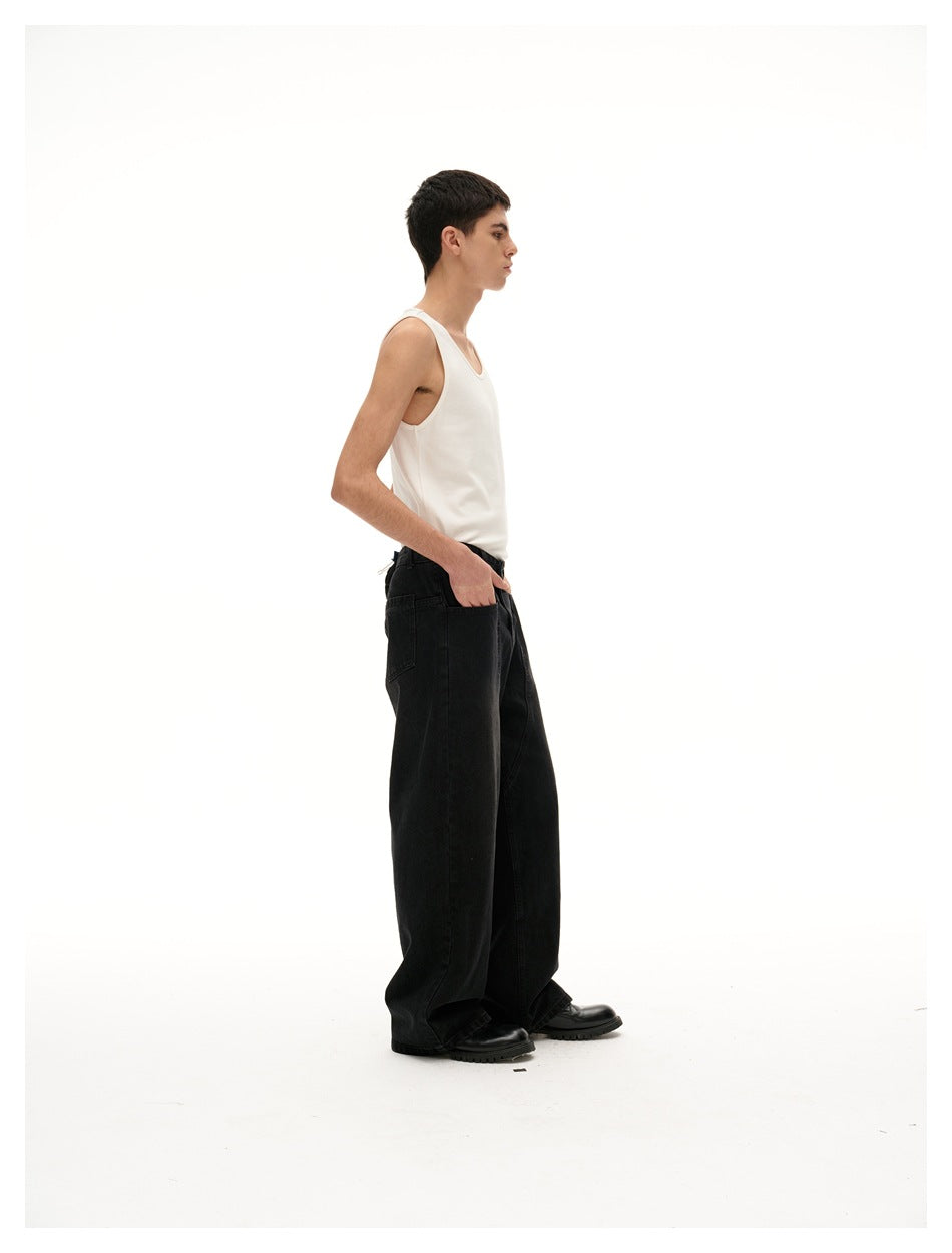Side-profile view of a model wearing a white tank top and loose, wide-leg black jeans.