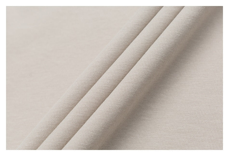 Close-up of light beige fabric arranged in soft folds, showing its fine knit texture.