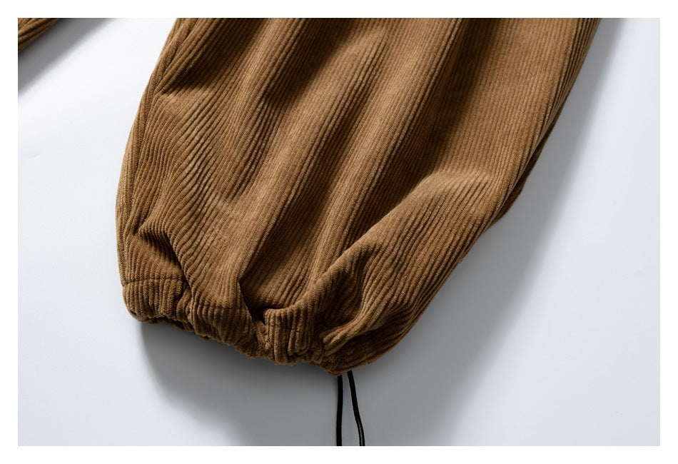 Close-up showing the gathered hem and ribbed texture of the brown corduroy trousers.