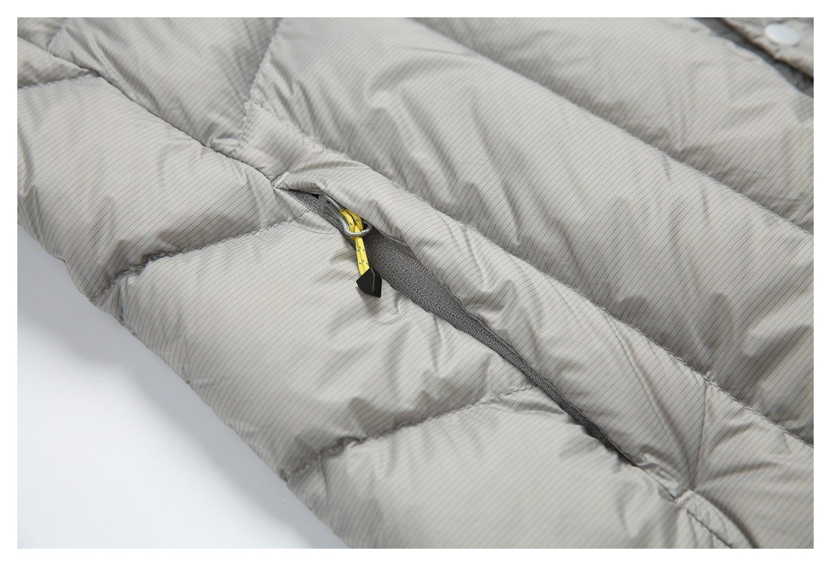 Close-up of a gray jacket pocket with a yellow cord zipper pull and quilted pinstriped fabric.