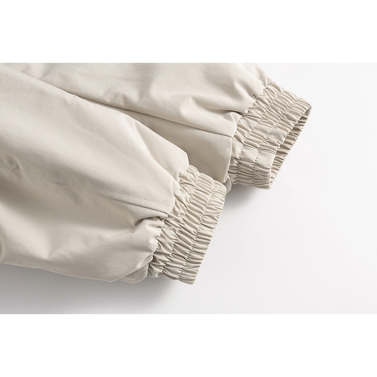 Close-up of the light beige jacket's gathered elastic cuffs and sleeve seams.