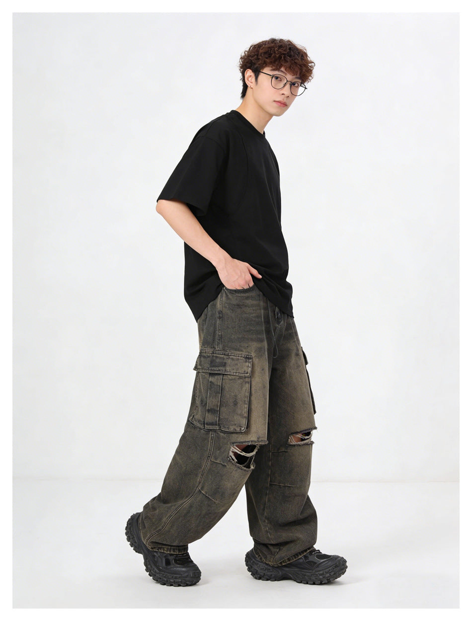 Model in a black T-shirt and distressed cargo jeans, turned sideways with one hand in pocket