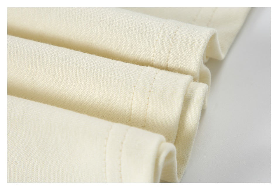 Close-up of several folded cream garment hems with visible stitching.