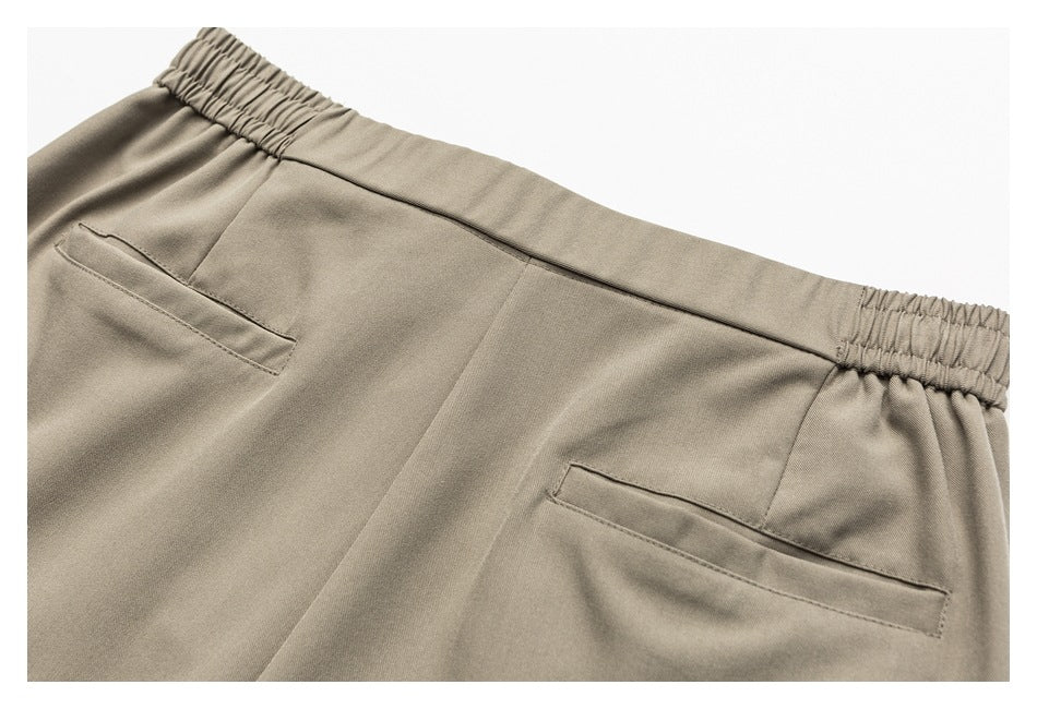 Back view of taupe trousers showing an elasticated waistband and two slim welt pockets.