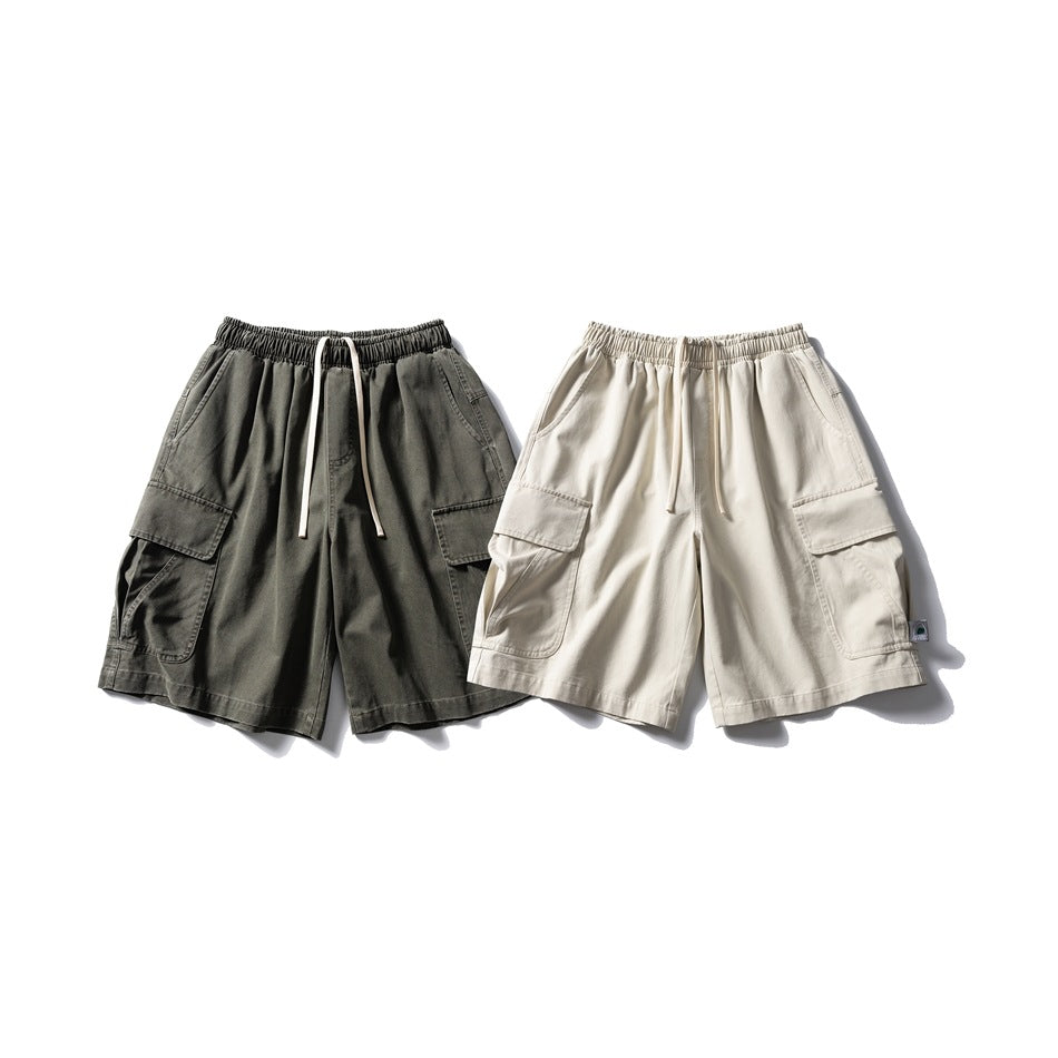 Two pairs of cargo shorts shown flat, in charcoal gray and cream, with elastic waists and drawstrings.