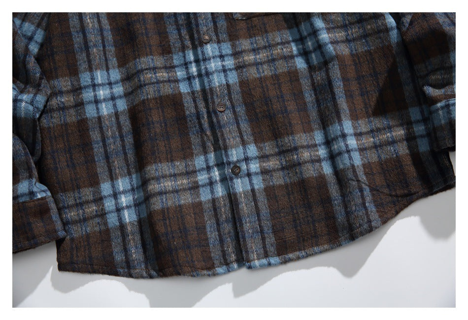 Cropped flat lay of the shirt front, showing brown and blue plaid, buttons, and the lower hem.