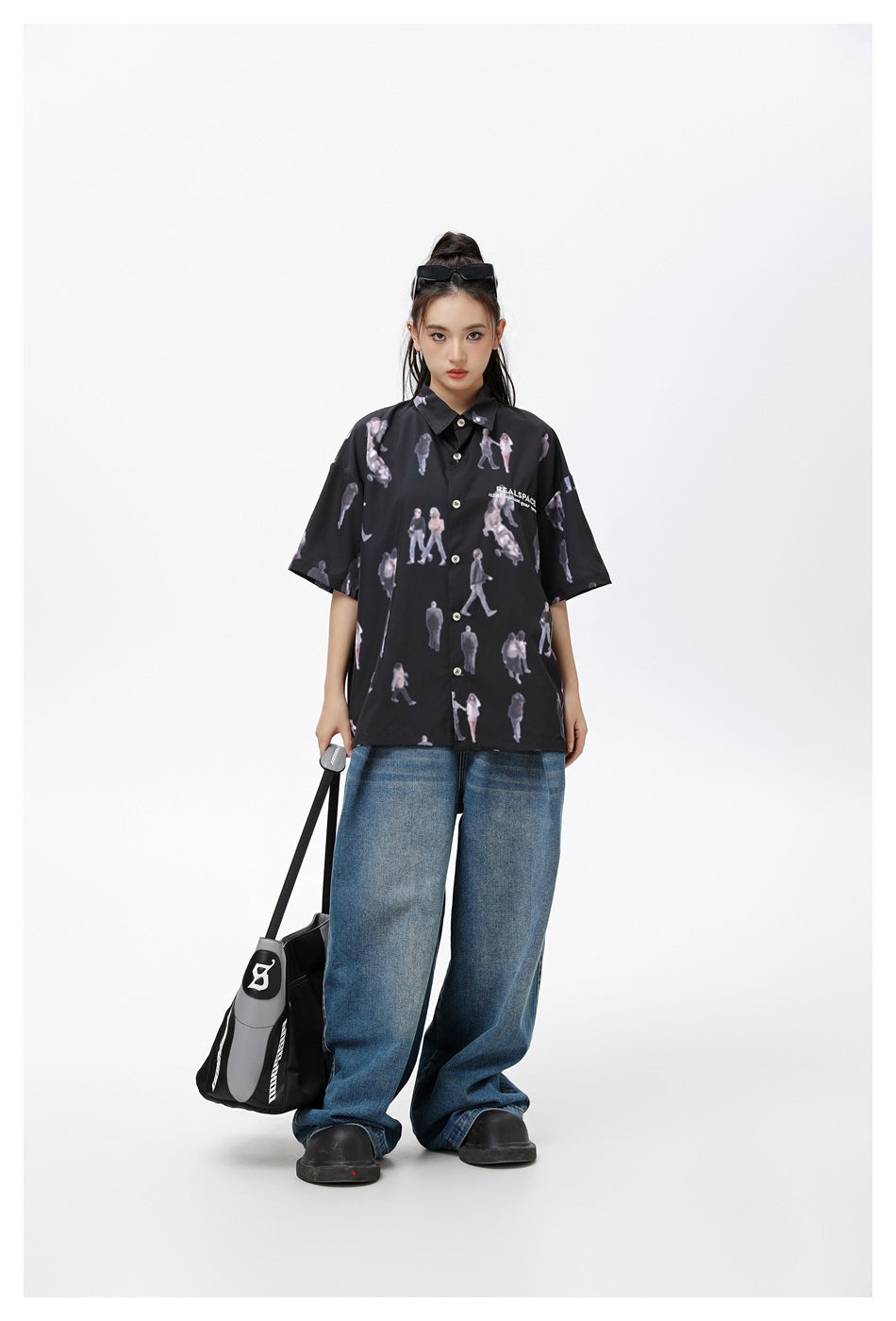 Model wearing the black figure-print short-sleeve shirt with loose blue jeans.
