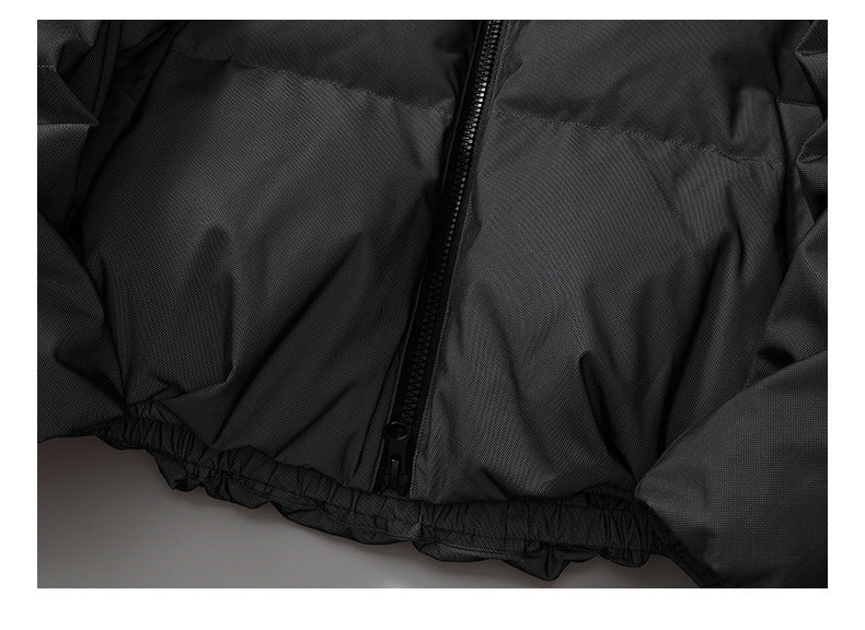 Close-up of the black jacket's front zipper and gathered elastic hem.