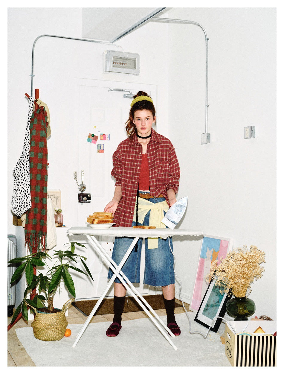 Full-length model wearing a red plaid button-up shirt with denim culottes and a cream layer tied at the waist.