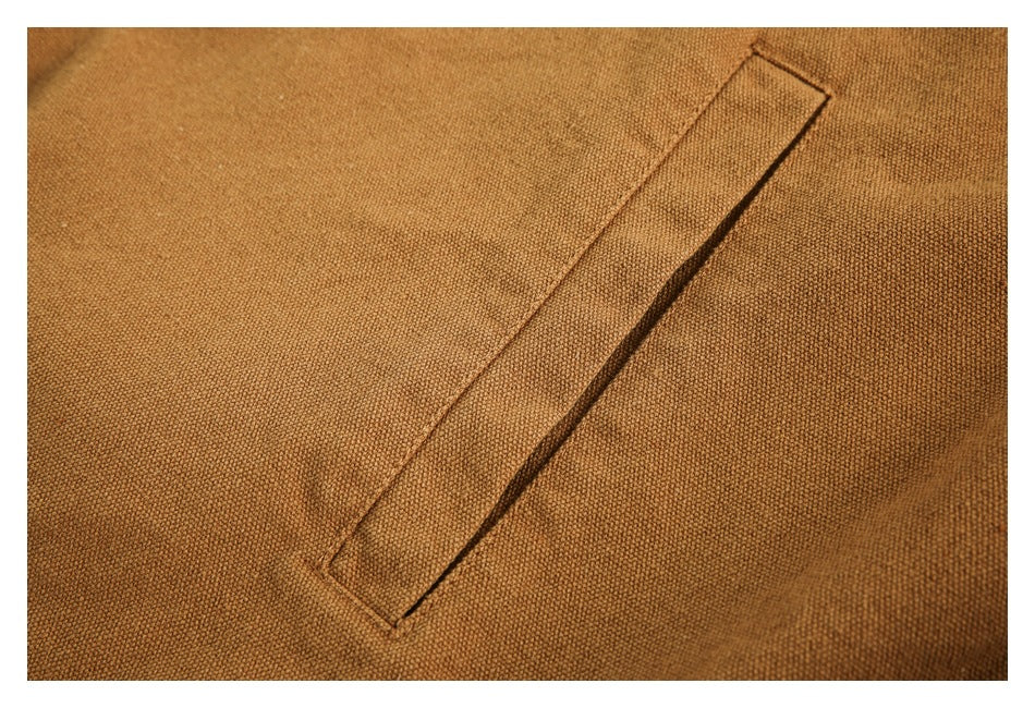 Close-up of a diagonal welt pocket on a textured camel-brown garment.