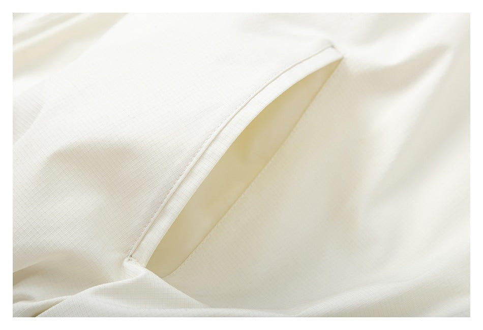 Close-up of an ivory garment's curved seam and narrow pocket opening.