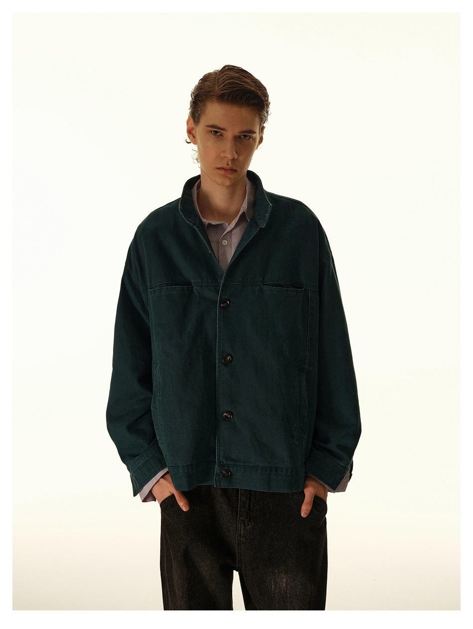 Male model wearing a dark teal button-up jacket over a lavender shirt with dark jeans, front view