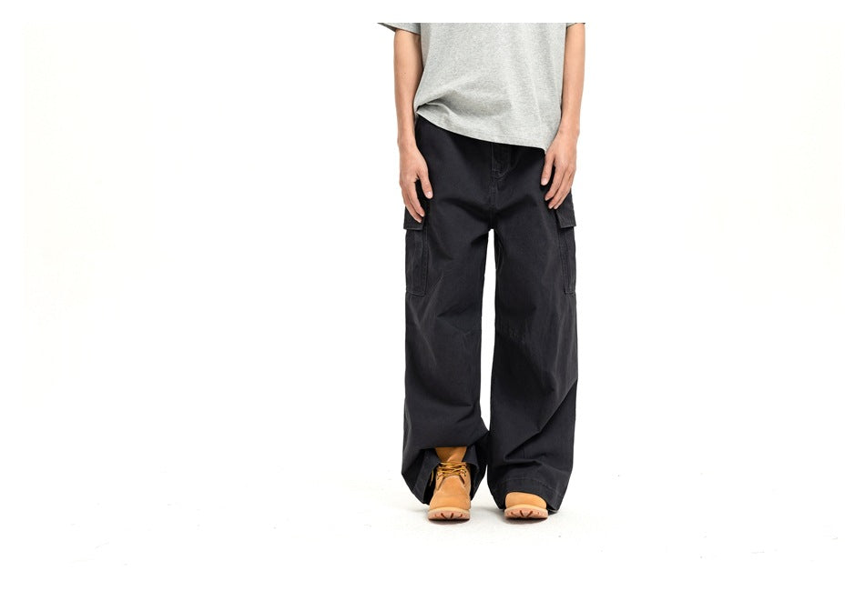 Cropped front view of a model wearing loose black cargo pants with side pockets and tan shoes.