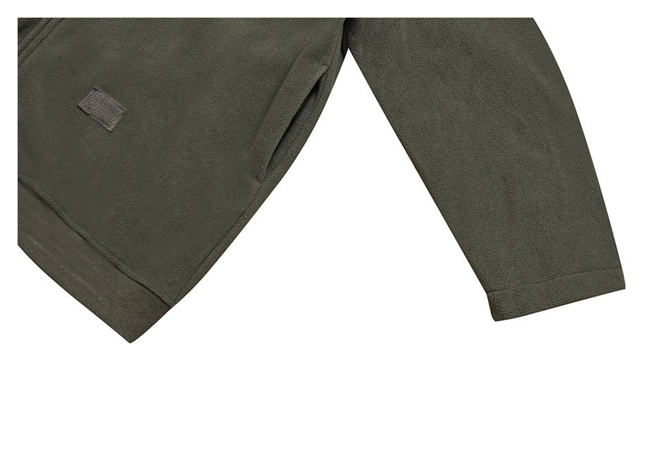 Cropped view of a dark olive fleece garment showing a sleeve, ribbed hem, and small blank fabric patch.