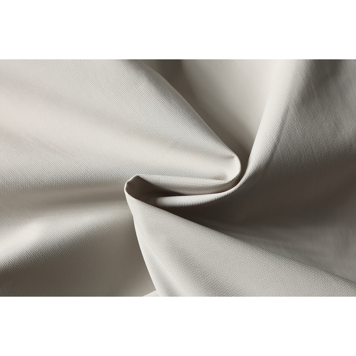 Close-up of the light beige shorts fabric draped to show its fine texture and folds.