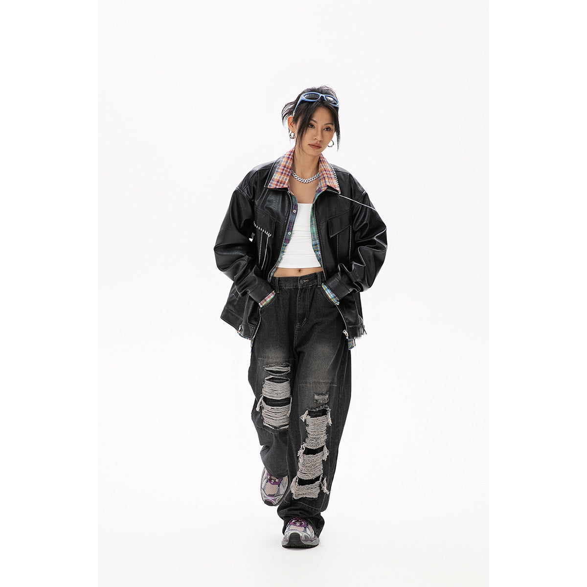 Model wearing an oversized black jacket with white stitch accents and a colorful plaid shirt.