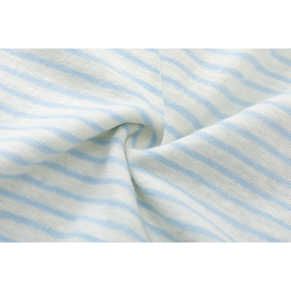 Close-up of the folded, softly draped ivory and pale blue striped shirt fabric.