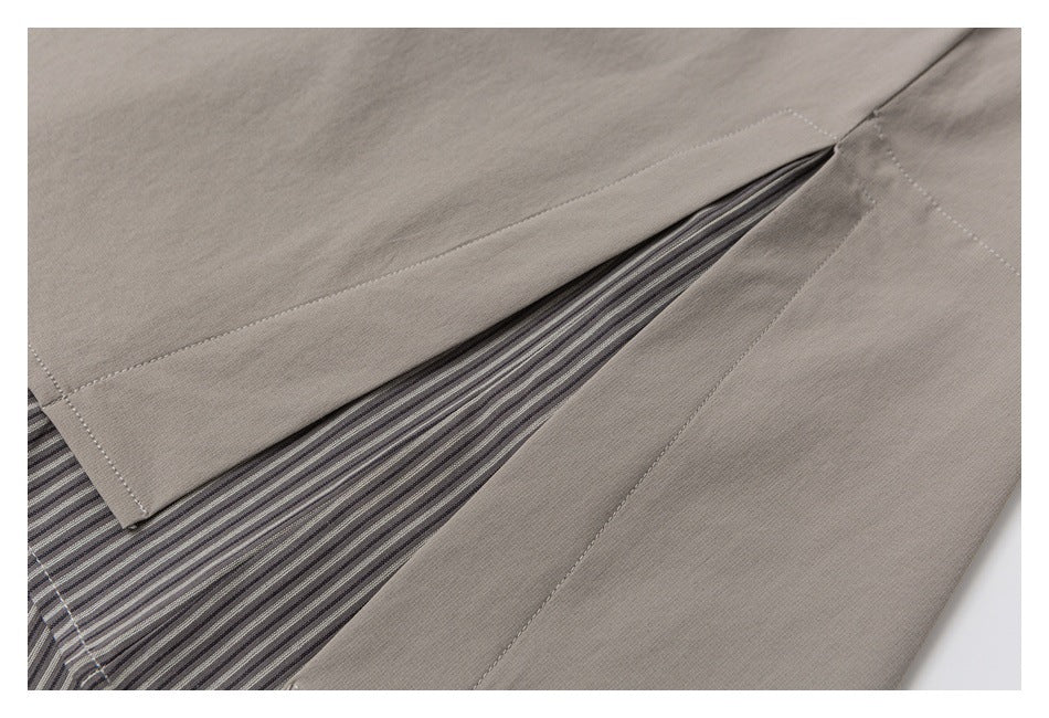 Close-up of a taupe shirt side vent revealing gray striped fabric underneath.