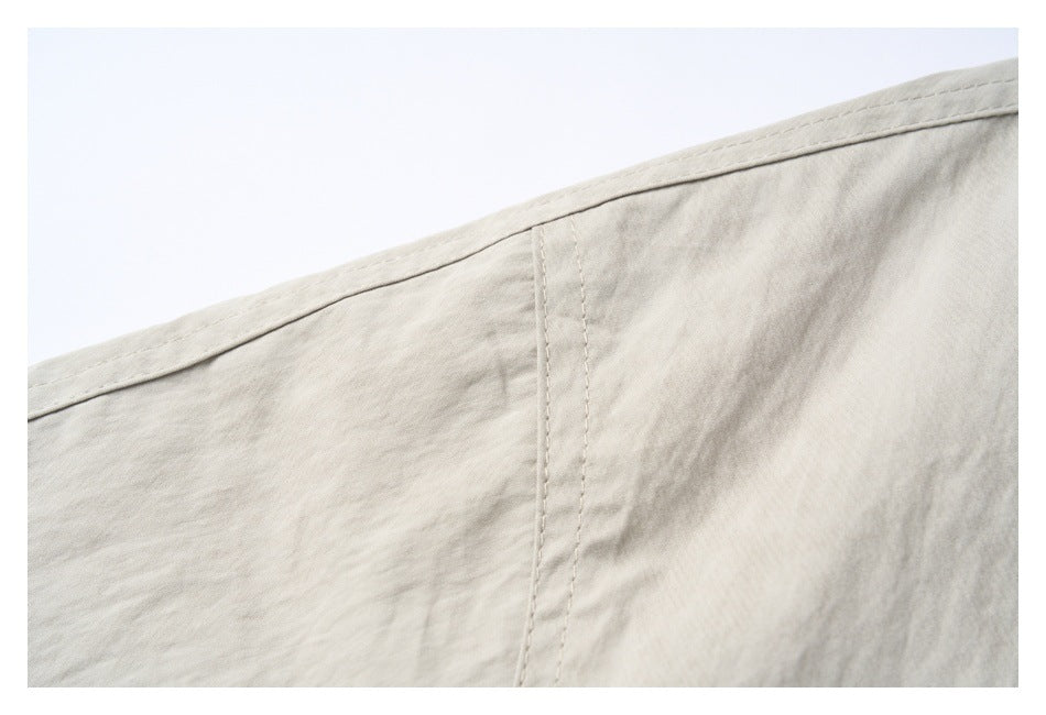 Close-up of a light beige-gray jacket showing a stitched seam and fabric texture.