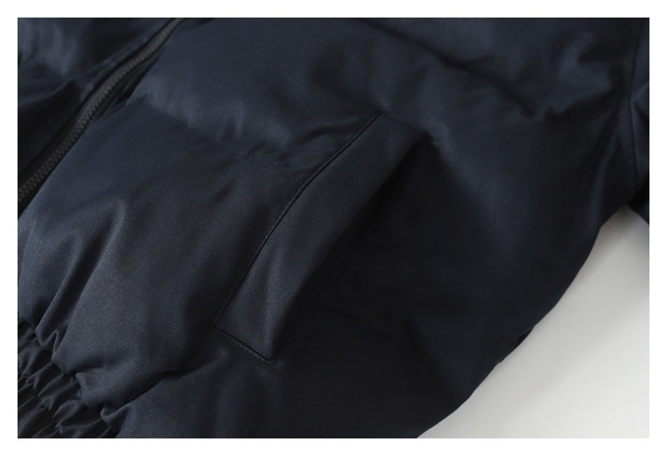 Close-up of a dark navy jacket showing a slanted pocket, zipper edge, and gathered elastic hem.