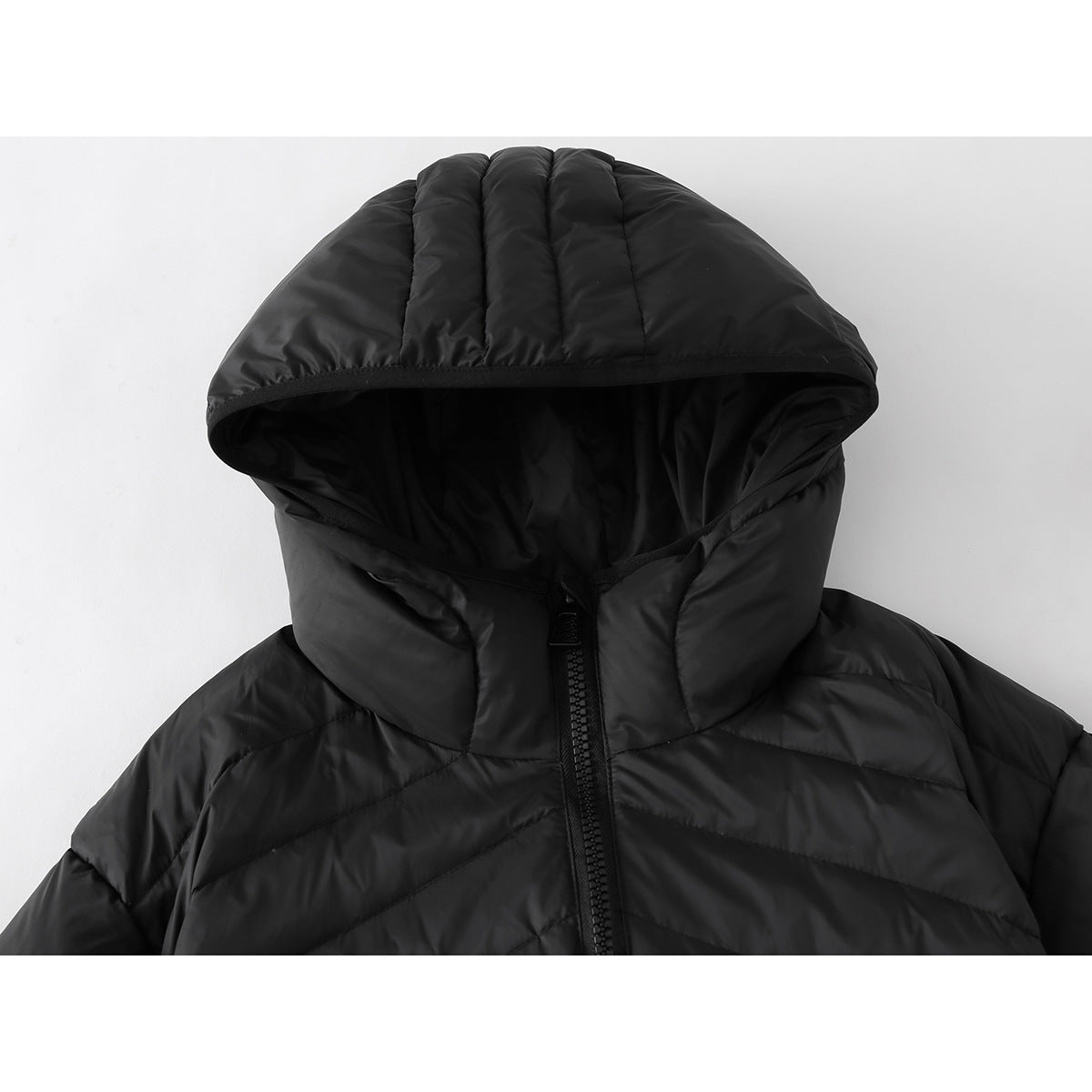 Close-up of a black quilted jacket's padded hood, high collar and front zipper.