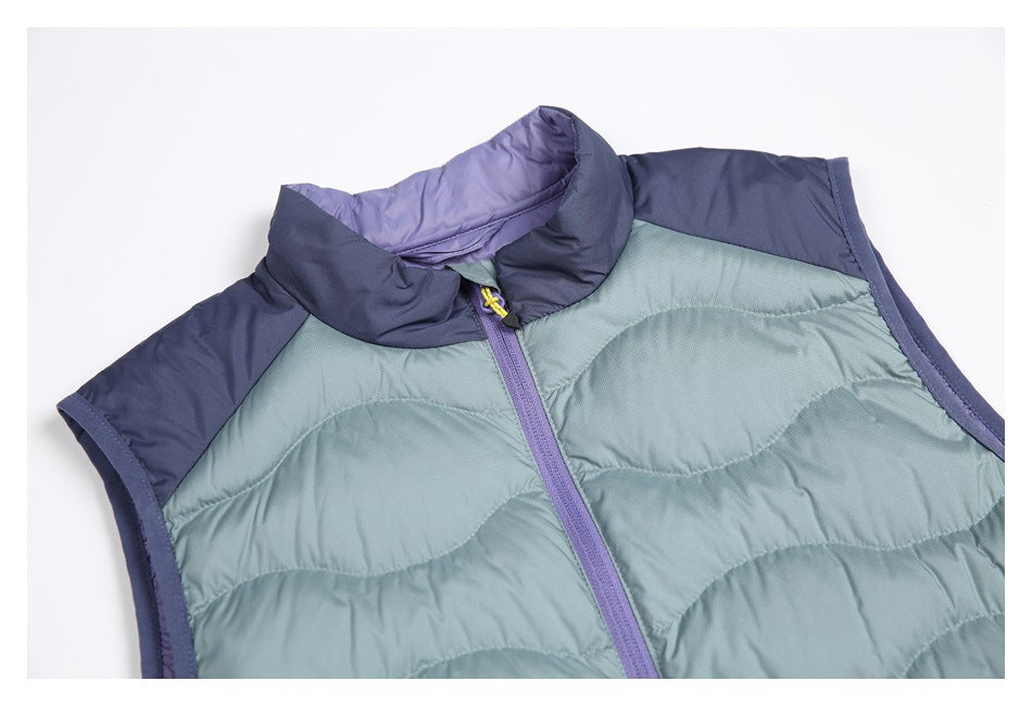 Close view of a quilted sleeveless vest in muted green-blue with navy shoulder panels and a purple zipper and collar.