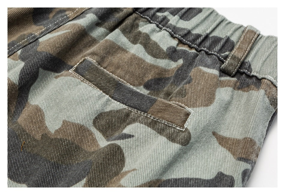 Close-up of camouflage trousers showing an elastic waistband, belt loop, and pocket opening.
