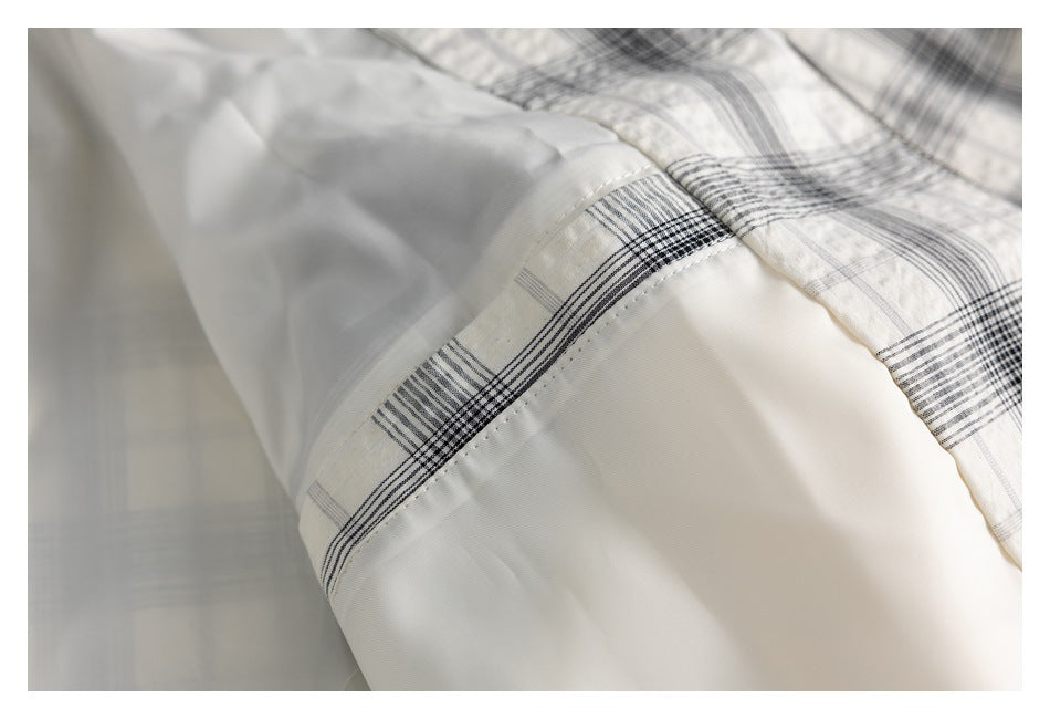 Close-up of a light plaid jacket panel joined to smooth white lining with a stitched seam.