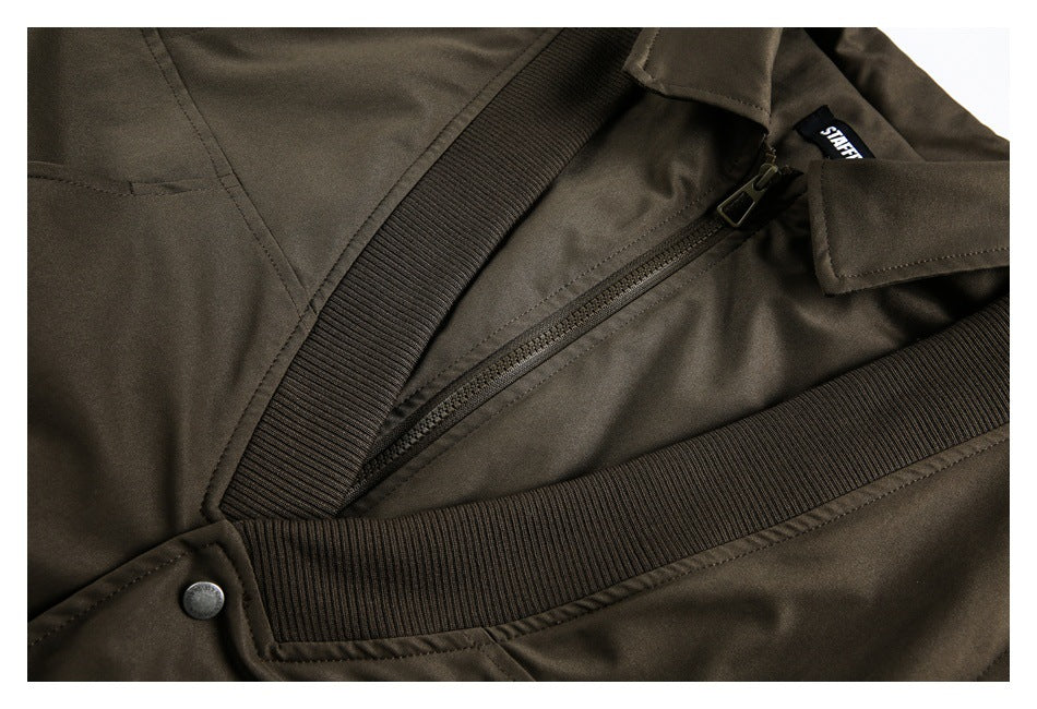 Close-up of the jacket's front zipper, ribbed waistband and a snap fastener.