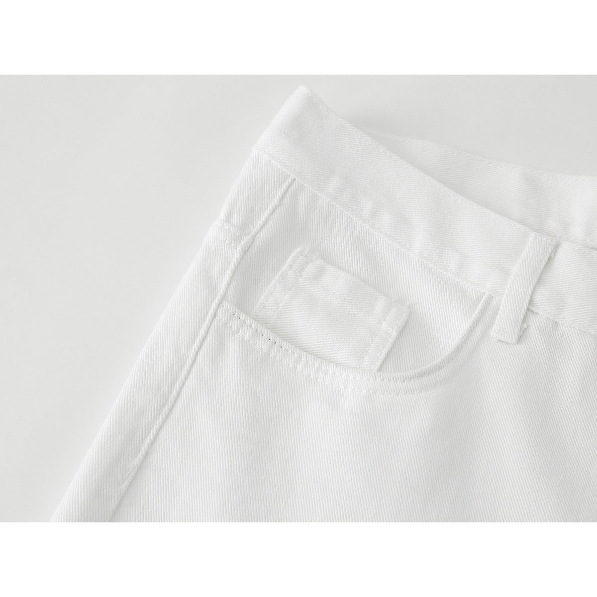 Close-up of the white pants' front pocket, small coin pocket, waistband, and belt loop.