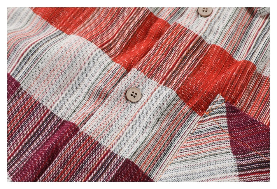Close-up of a button and chest pocket on the shirt's red, cream, and burgundy plaid fabric.