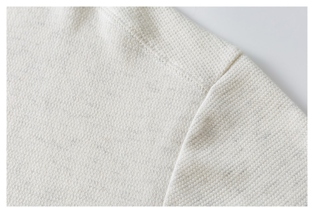 Close-up of the shoulder seam on an ivory textured top.