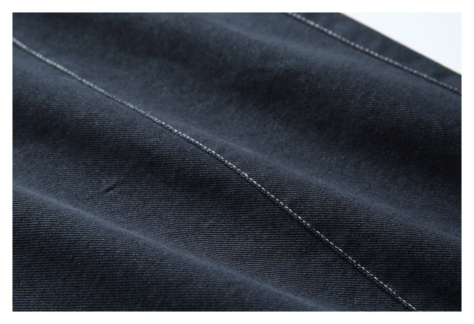 Close-up of dark denim fabric with diagonal contrast stitching.