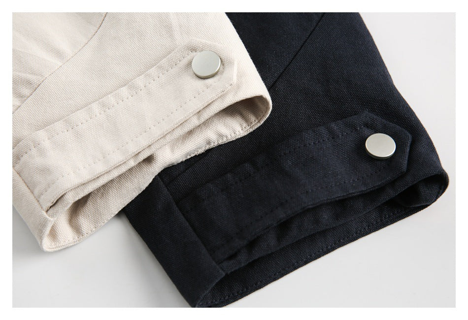 Close-up of off-white and black jacket sleeve cuffs with metal snap buttons.