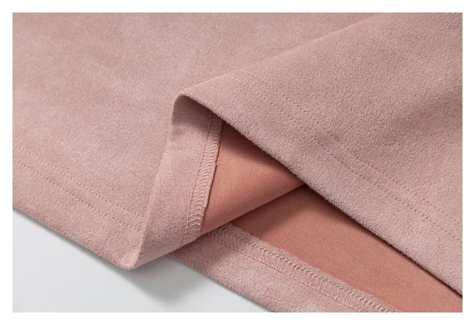 Close-up of dusty rose fabric showing a folded hem, overlock stitching, and the garment's inner side.