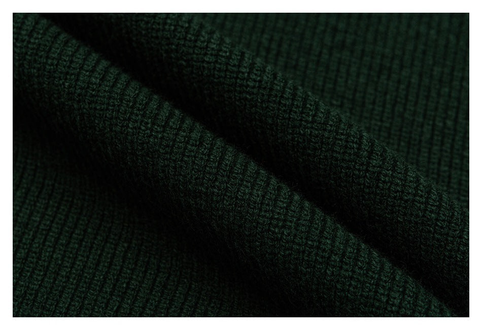 Extreme close-up of the dark green garment's textured knit fabric.