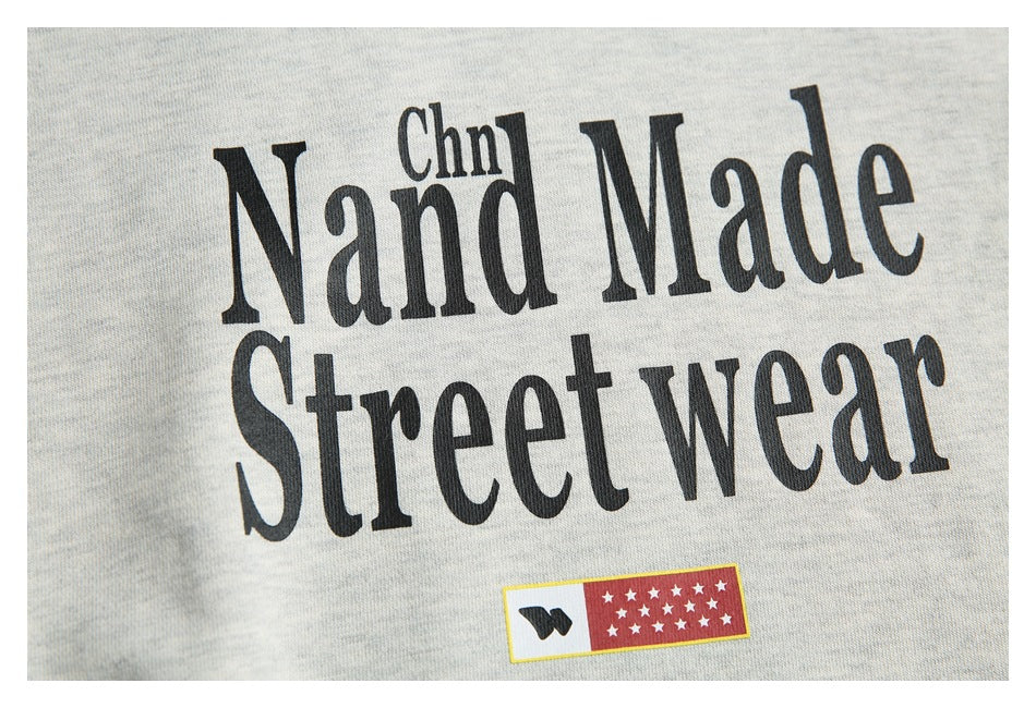 Close-up of black “Nand Made Street wear” lettering and a small red star graphic on a light gray hoodie.