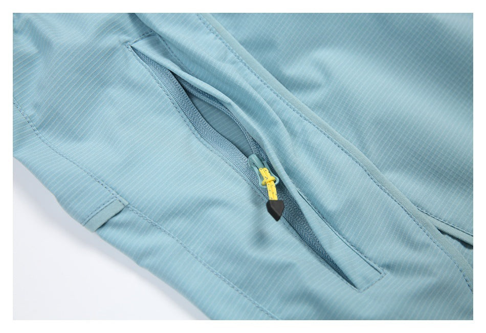 Close-up of a pale blue garment with a diagonal zip pocket and yellow-and-black zipper pull.