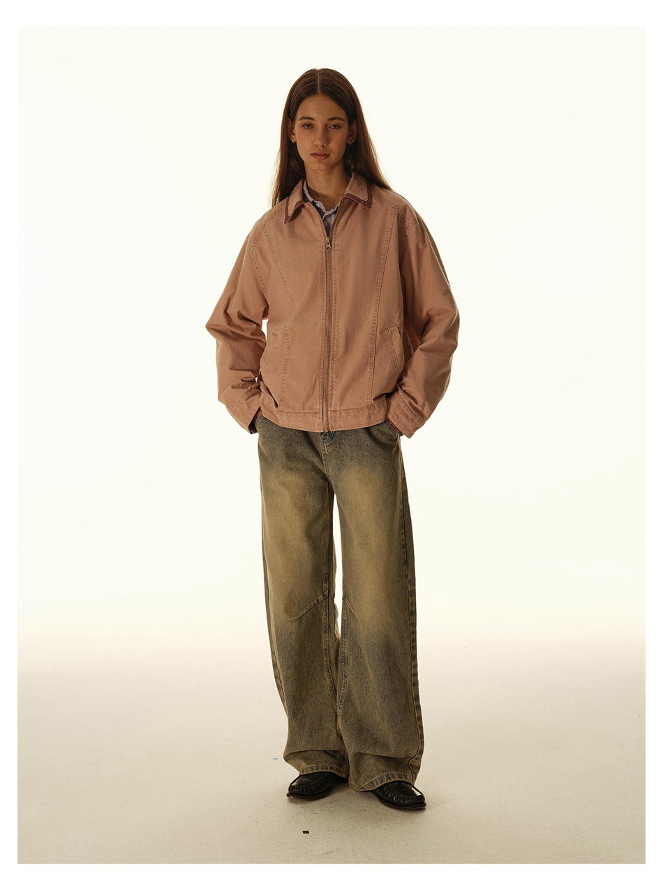 Model wearing a dusty rose zip-front jacket with a pointed collar and roomy sleeves, paired with wide-leg olive jeans.