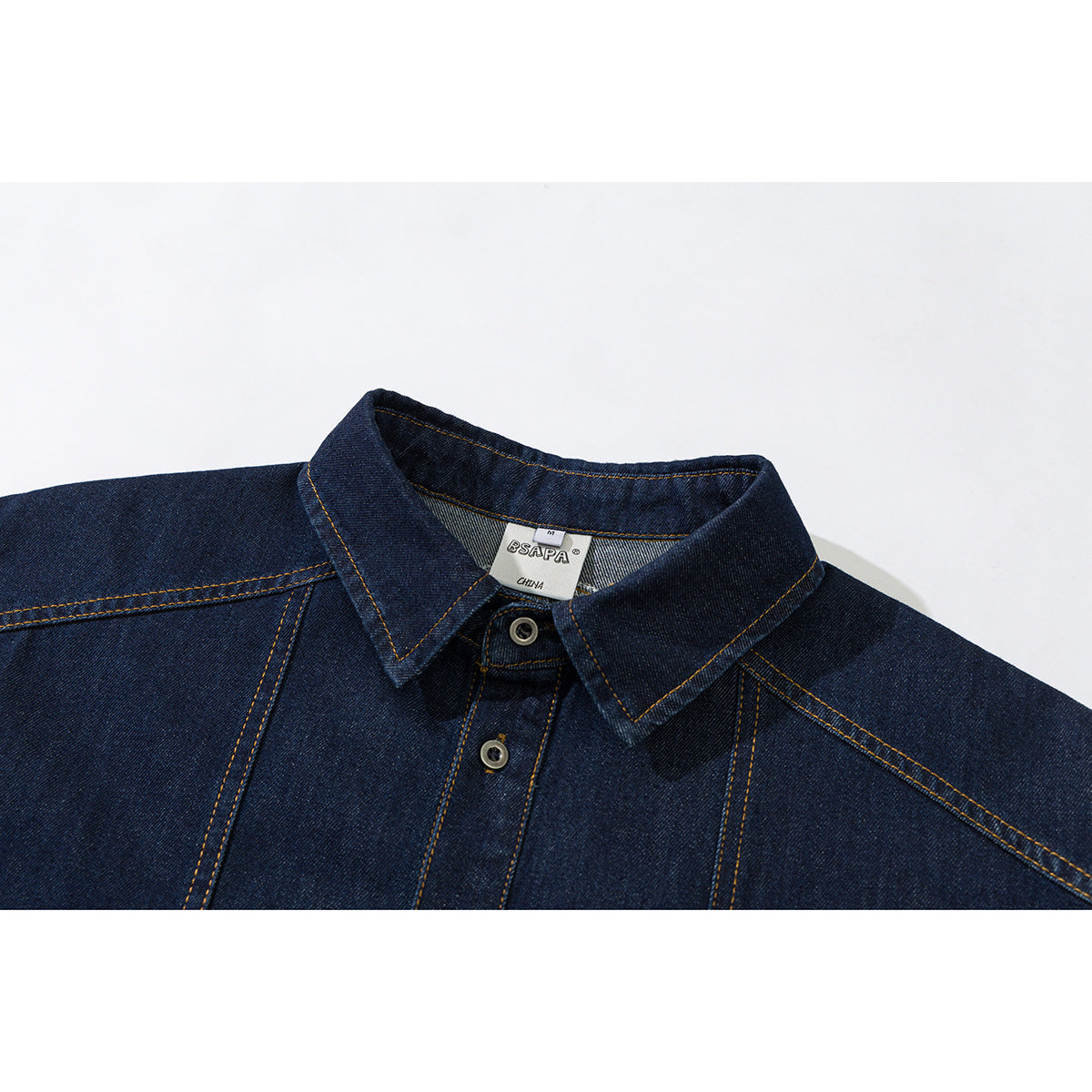 Close-up of a dark indigo denim shirt collar, button placket, and contrast stitching.