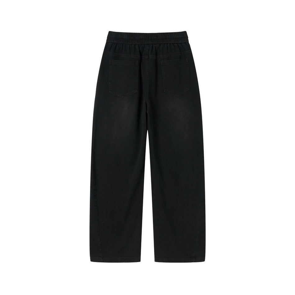Back view of black wide-leg pants with two patch pockets and elastic waistband, slightly faded wash