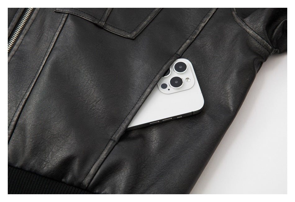 Close-up of a black jacket's angled pocket holding a white phone, with a silver zipper along the edge.