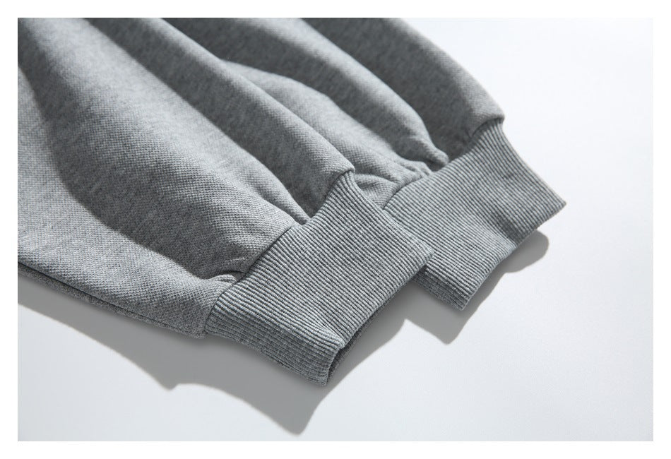 Close-up of two gray sweatshirt sleeves with ribbed cuffs.