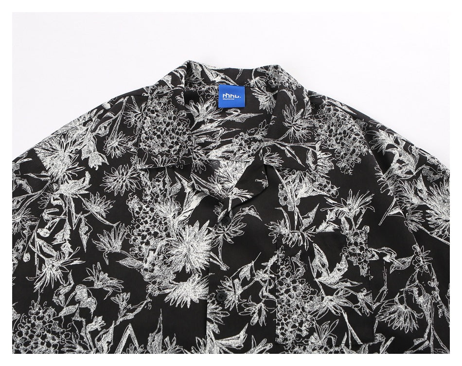 Close-up of the shirt's pointed collar, button placket and white botanical print on black.