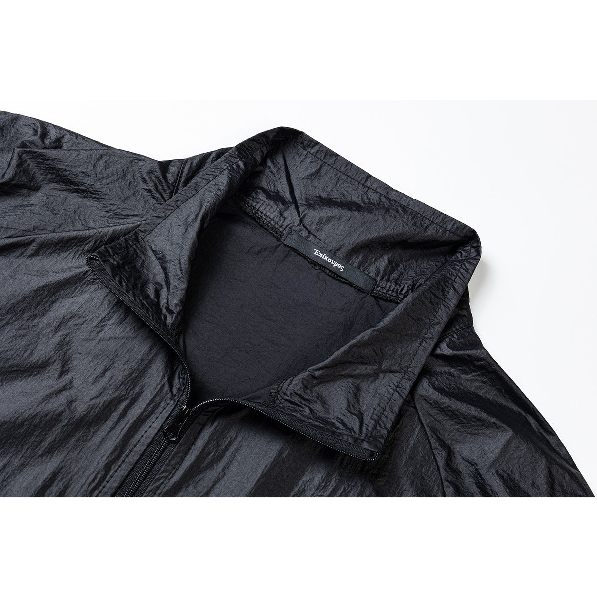 Close-up of a black crinkled jacket showing its raised collar, zipper, and inside neck label.