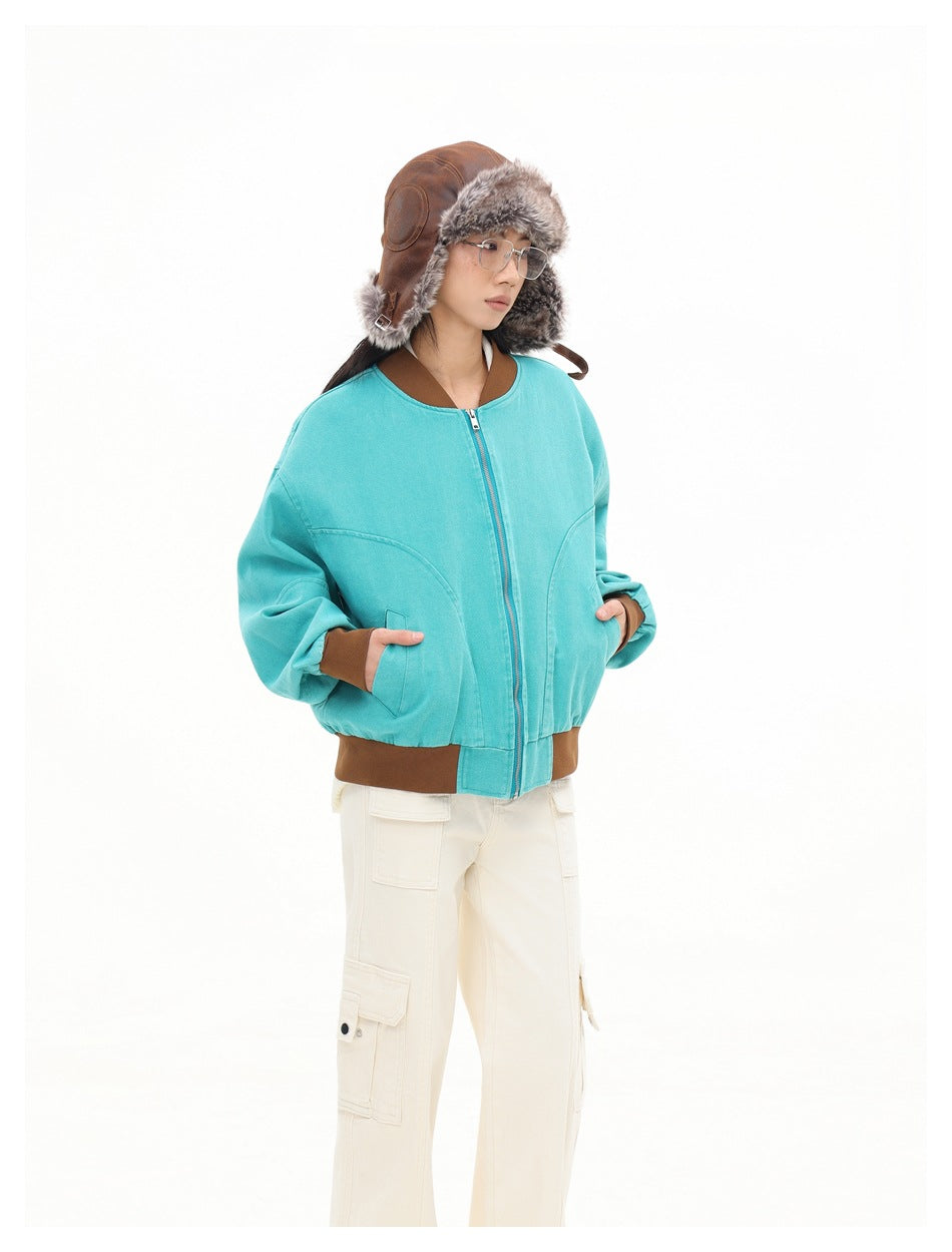 Model wearing a turquoise zip-front jacket with brown ribbed trim, paired with cream cargo trousers and a fur-lined brown