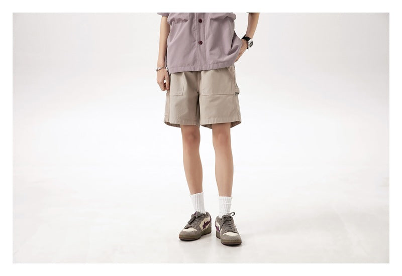 Cropped front view of a model wearing light beige cargo shorts with large front pockets.