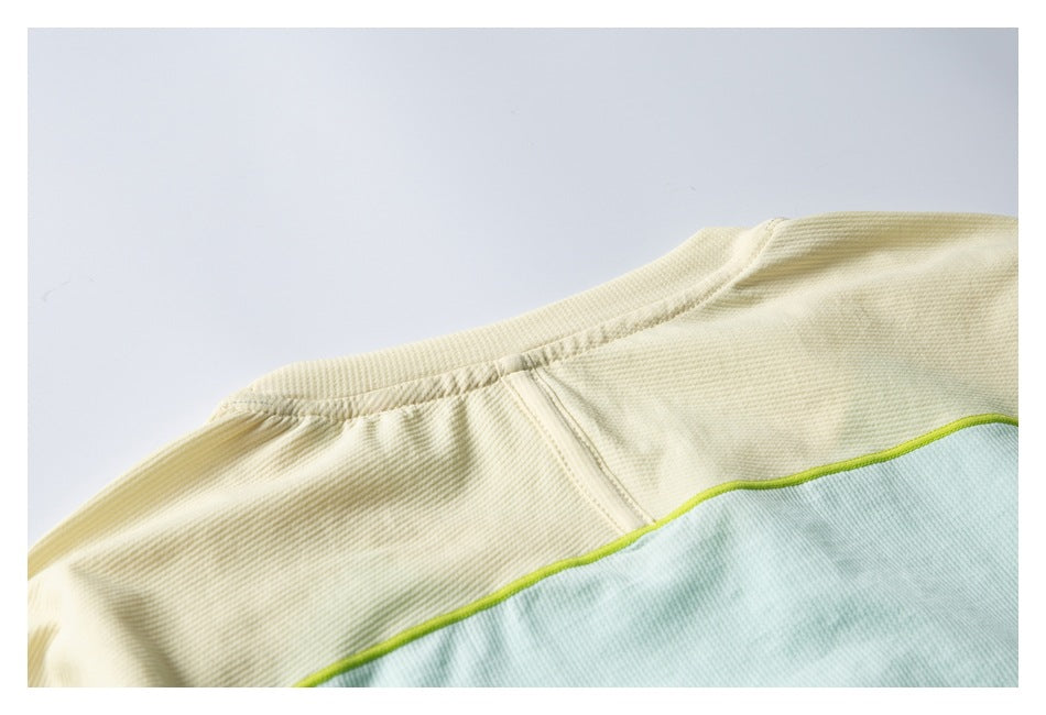 Close-up of a pale yellow and mint color-blocked garment shoulder with lime piping.