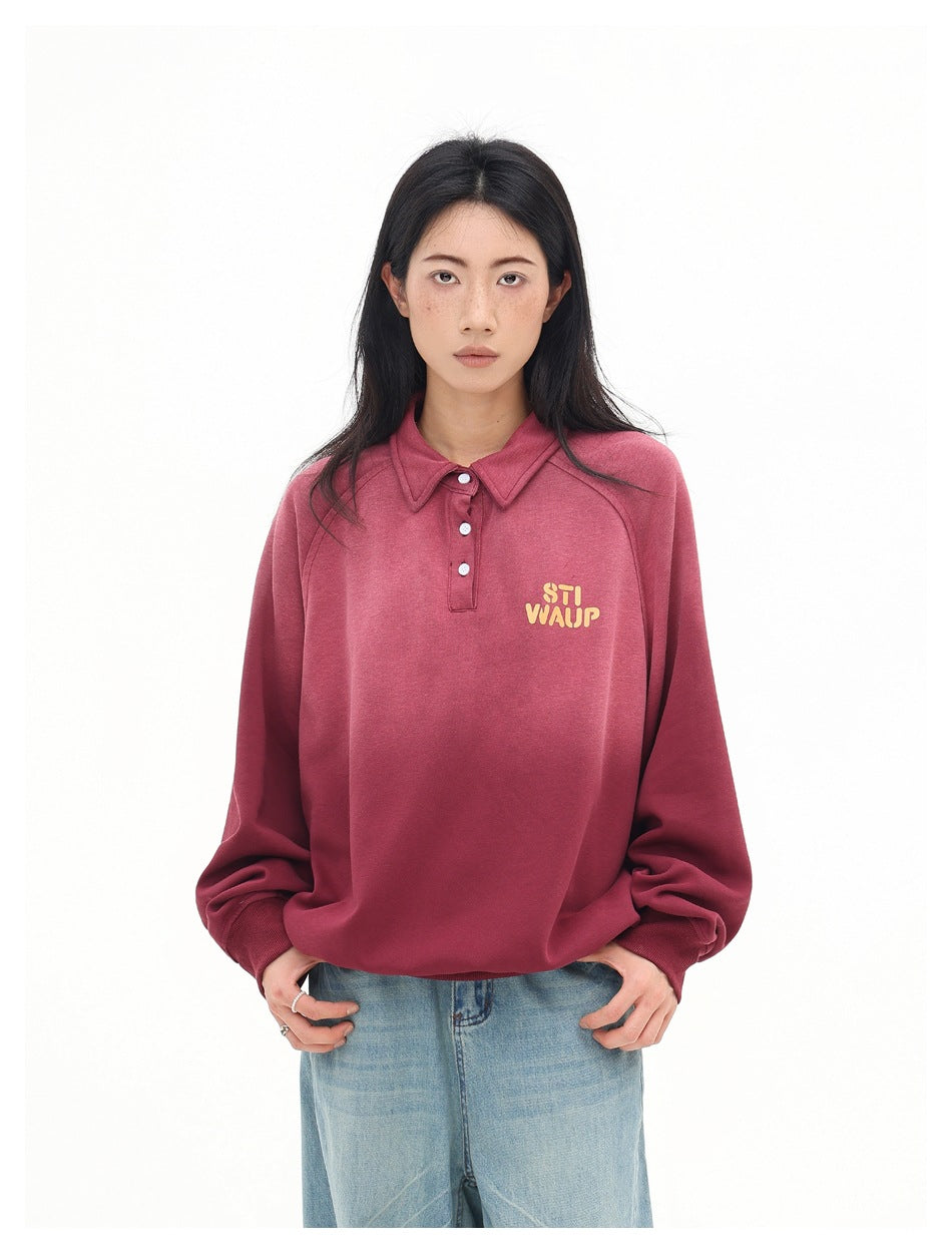 Model wearing a burgundy long-sleeve collared pullover with white buttons and small yellow chest lettering.