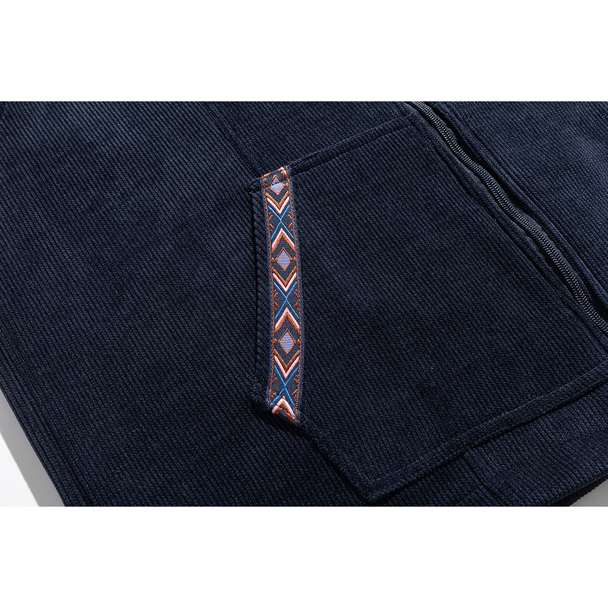 Close-up of a navy hoodie pocket with a narrow orange, blue and white geometric trim accent.